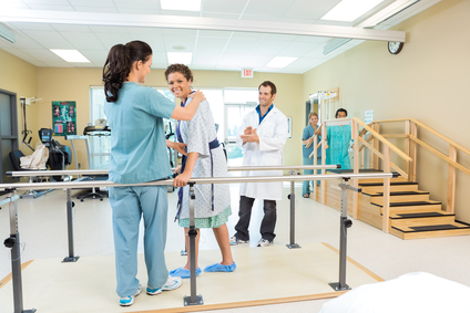 Portrait of female patient being assisted by physical therapist while doctor applauding